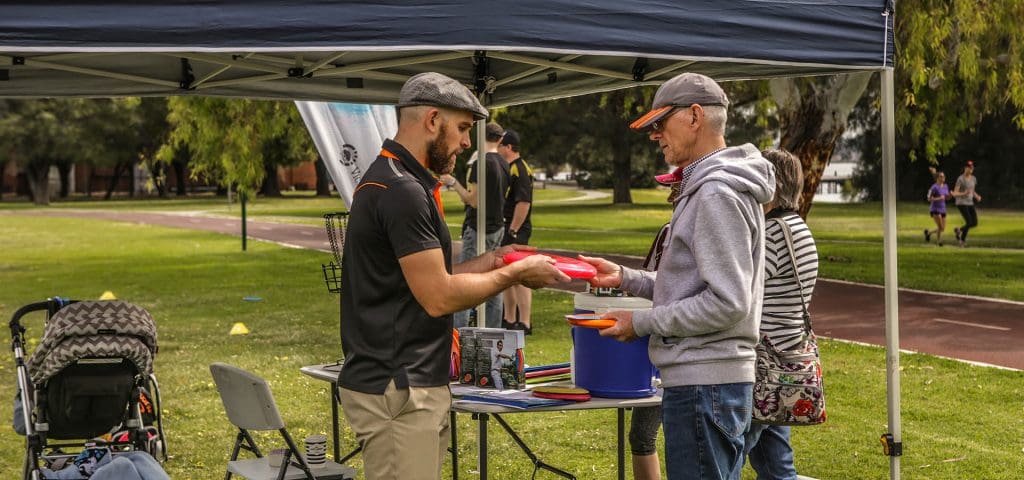 An image showing man people buying disc golf frisbee and two people running