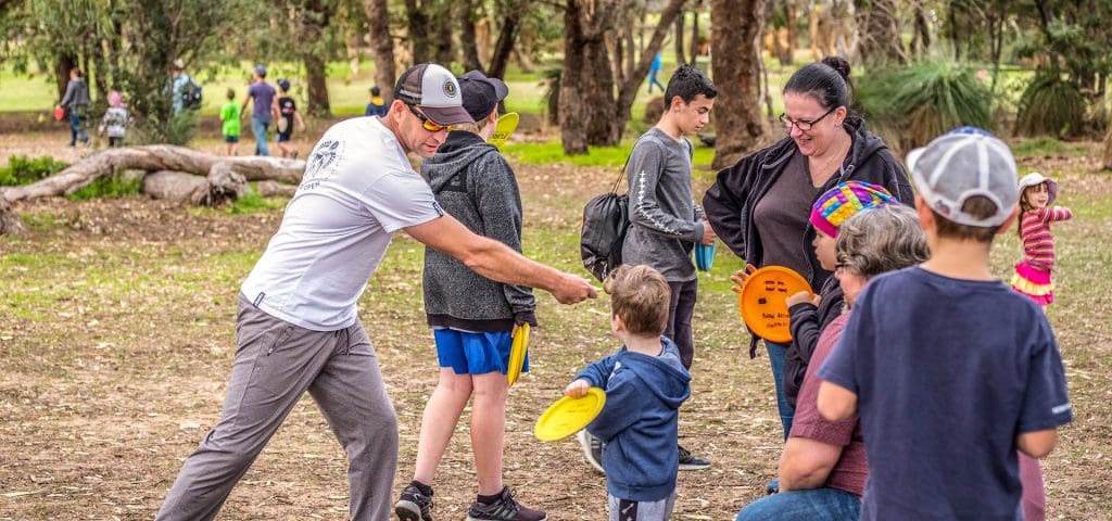 An image showing family playing disc golf frisbee in a park