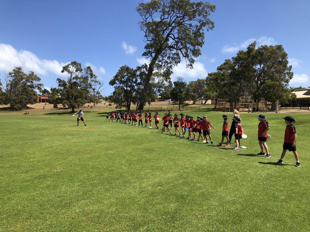 An image of young ones practicing playing disc golf in a field