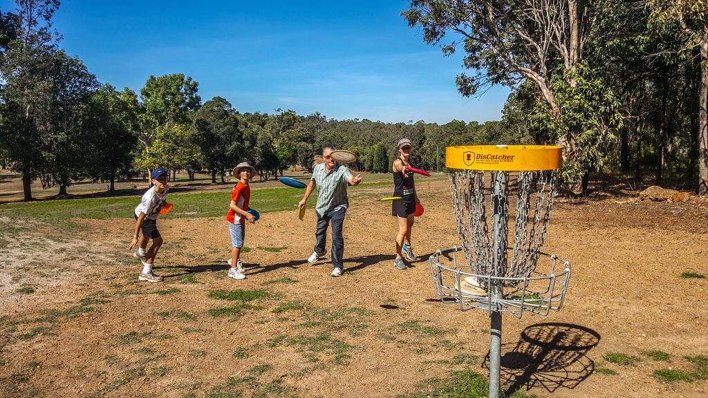 an image of people trying to shoot frisbee in a disc golf basket