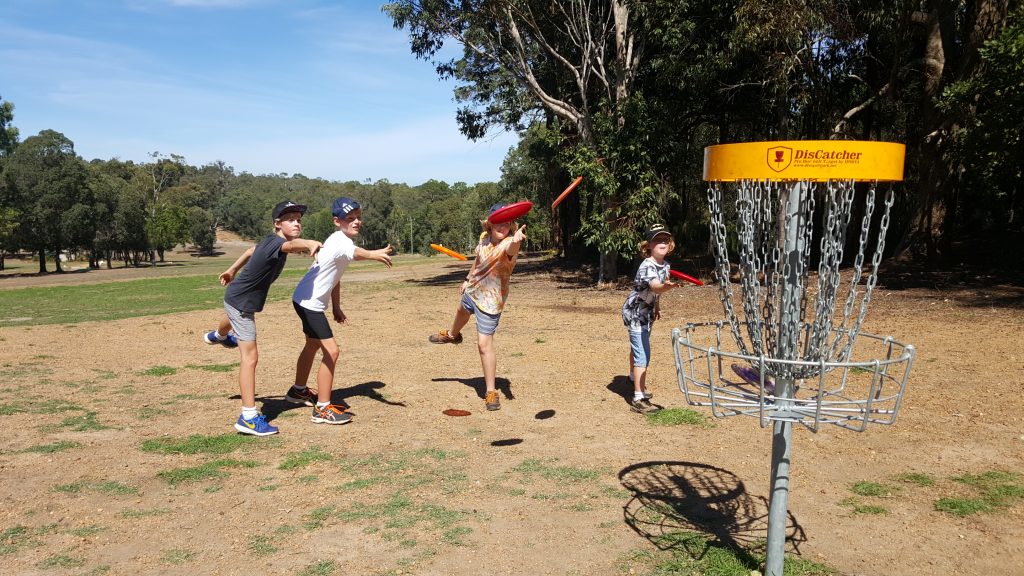 an image of children playing disc golf in a disc golf park