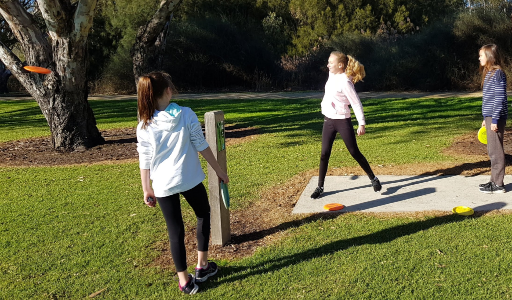 an image of three young women playing disc golf