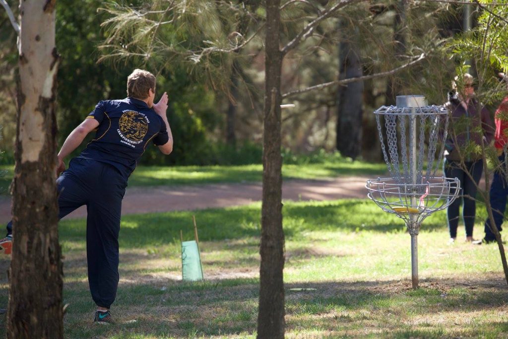 an image of a man playing disc golf in a park