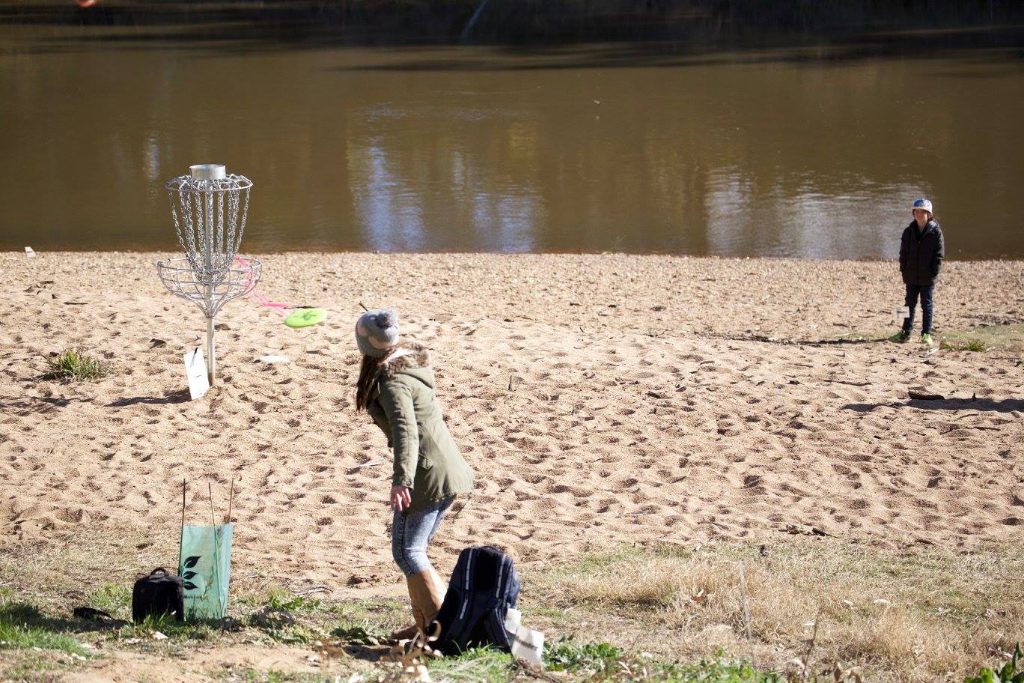 an image of a woman playing disc golf near the beach