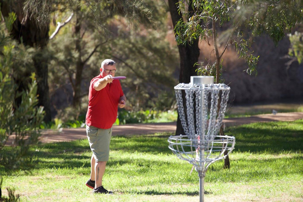 an image of man trying to shoot a disc golf in a target
