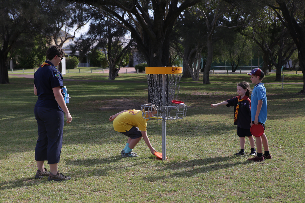 an image of kids and a lady playing disc golf