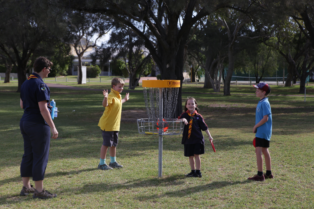 an image of kids and a lady playing disc golf