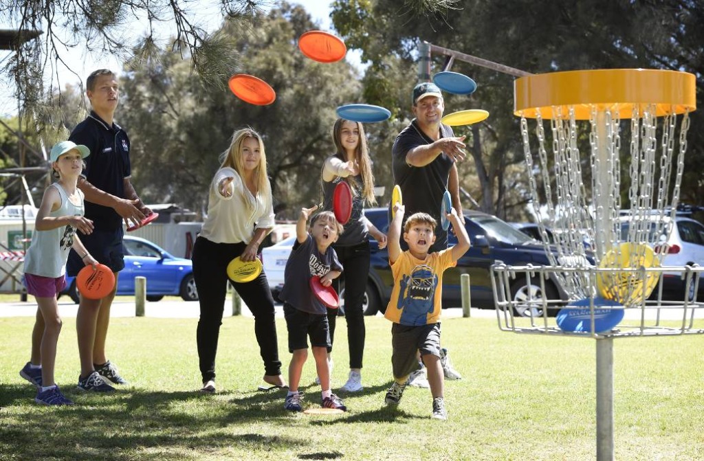 an image of kids and adults playing disc golf