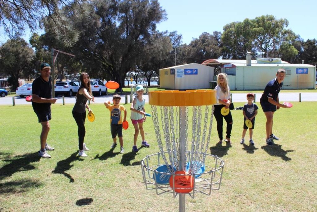 an image of kids and adults playing disc golf